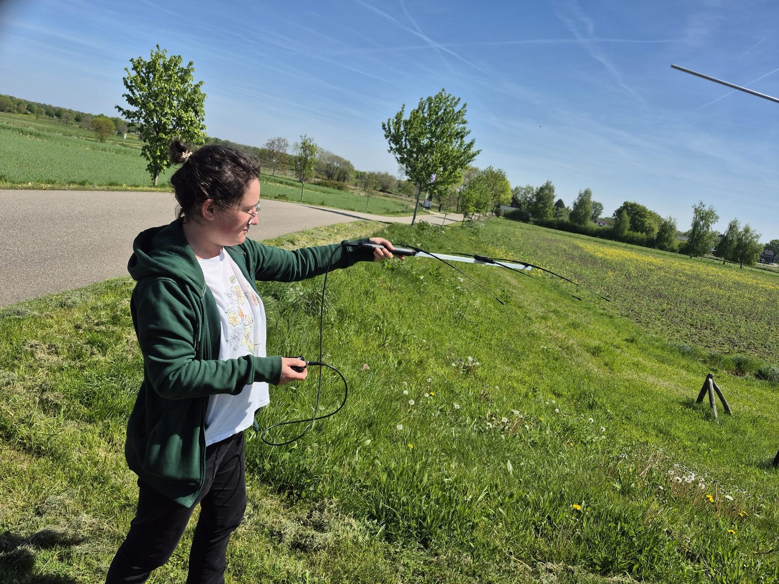 Ecoloog richt een handantenne op een veld tijdens telemetrie-onderzoek naar vleermuizen
